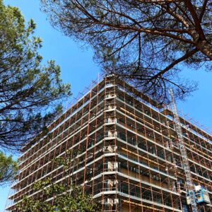 Edificio in costruzione con gru cielo azzurro e alberi